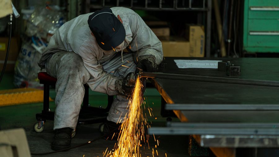 Métallier découpant une pièce d'acier en atelier