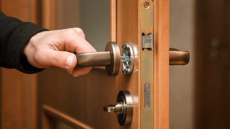 Main posant une serrure sur une porte