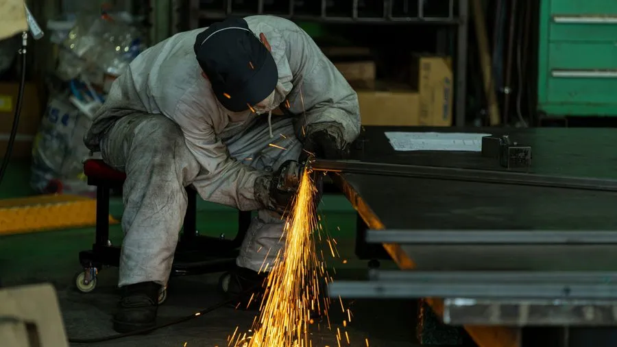 Métallier découpant une pièce d'acier en atelier