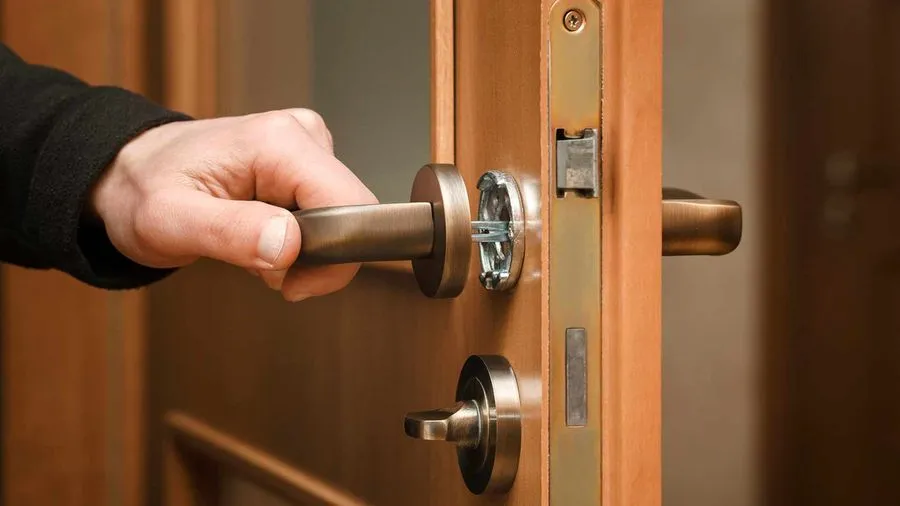 Main posant une serrure sur une porte